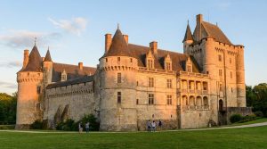 Vue extérieure du château de Fougères-sur-Bièvre illuminé par la lumière dorée du soleil couchant.
