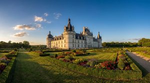 Vue panoramique du château de Valençay avec ses jardins fleuris et son architecture Renaissance sous un ciel bleu.
