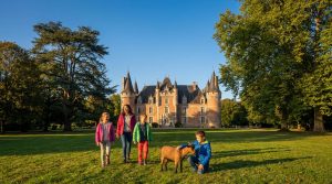 Une famille joue avec une chèvre sur la pelouse devant le Château de Villesavin sous un ciel bleu ensoleillé.